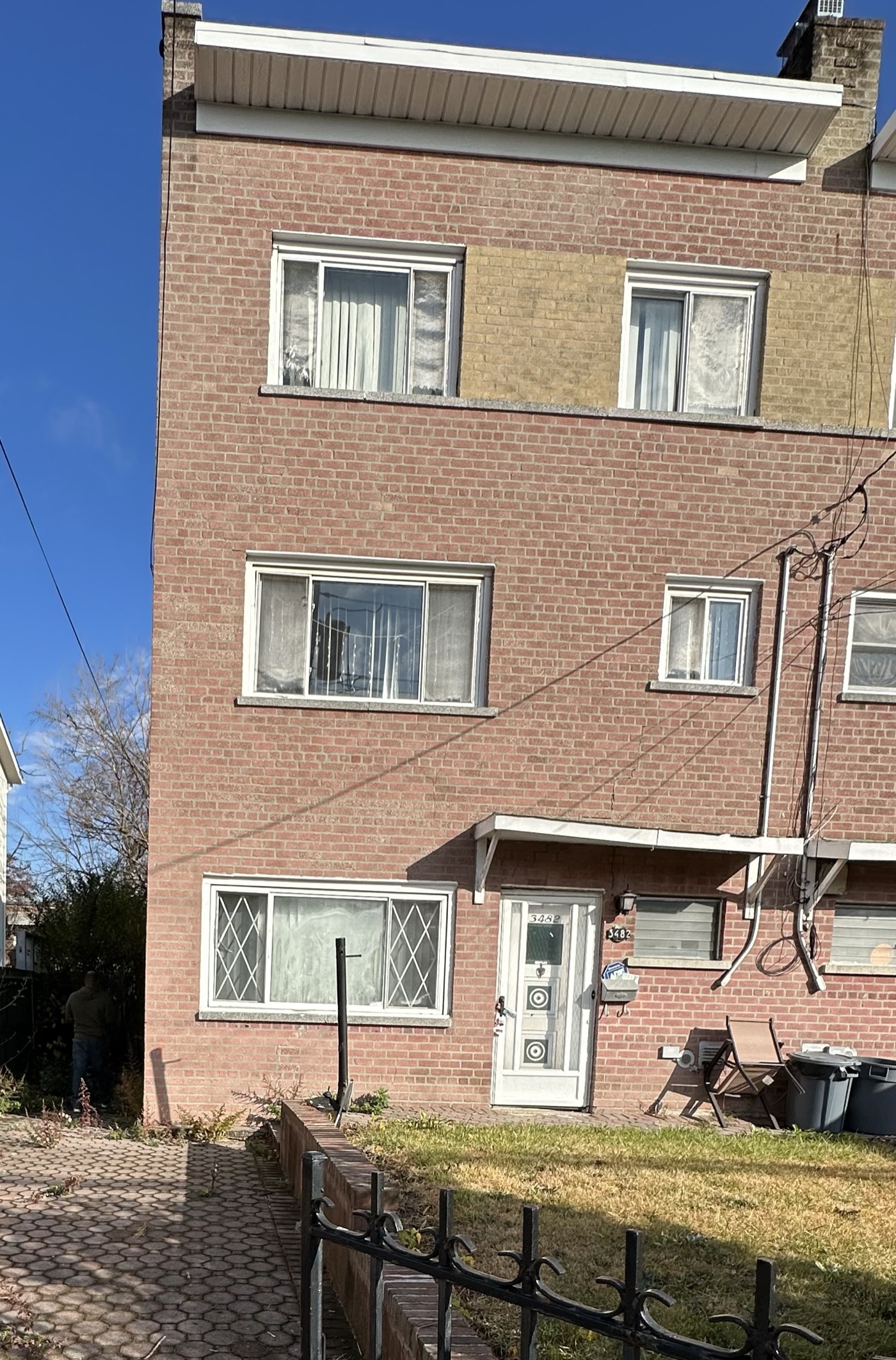 Three-storey brick multi-family house with a small front lawn, Bronx